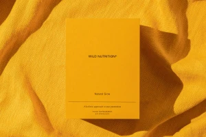 Yellow supplement box resting on textured amber fabric with soft shadow casting to the right