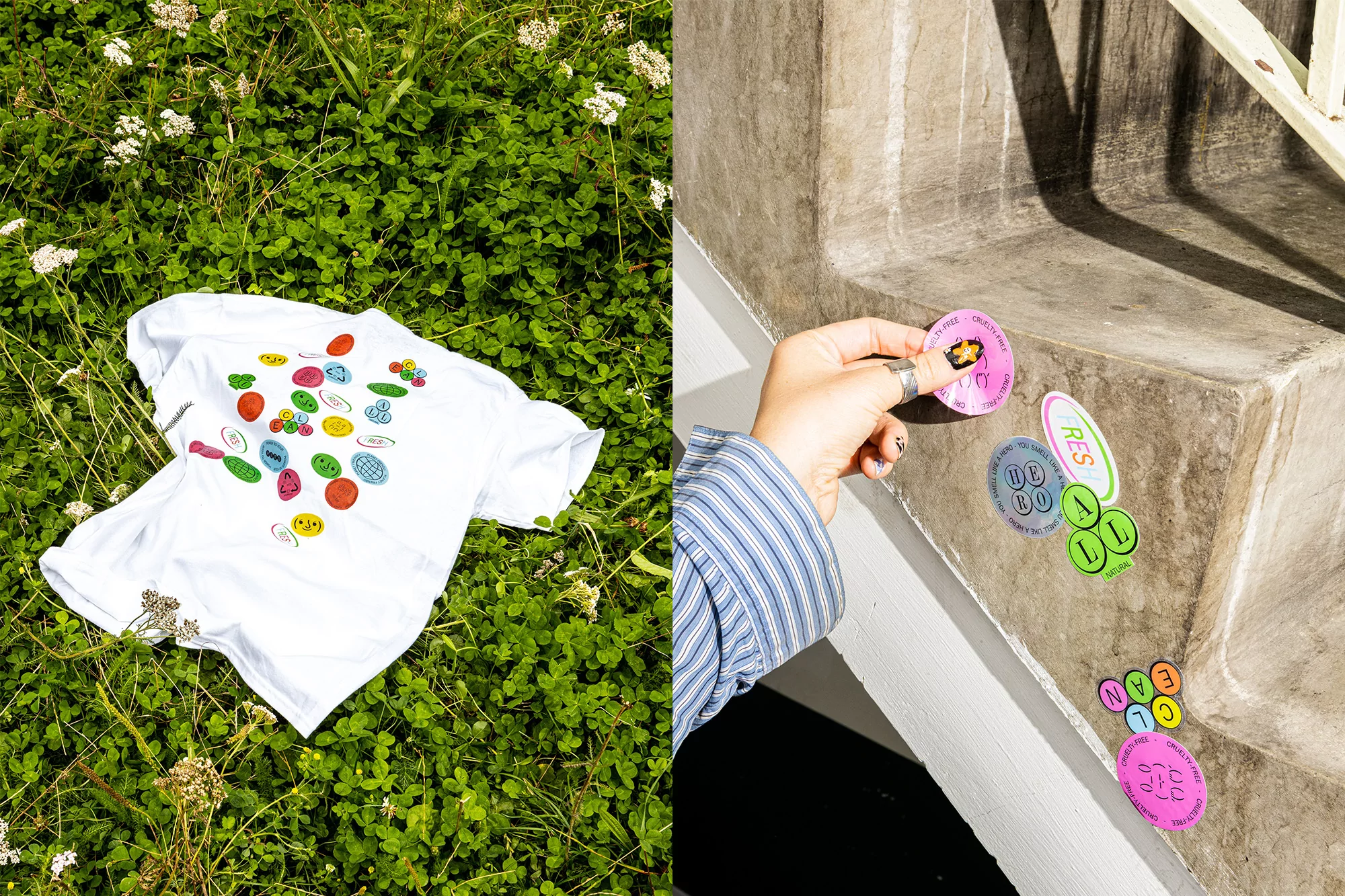 A white t-shirt with colorful cartoon graphics rests on green clover. Hand placing stickers on a concrete step, sunny daylight.