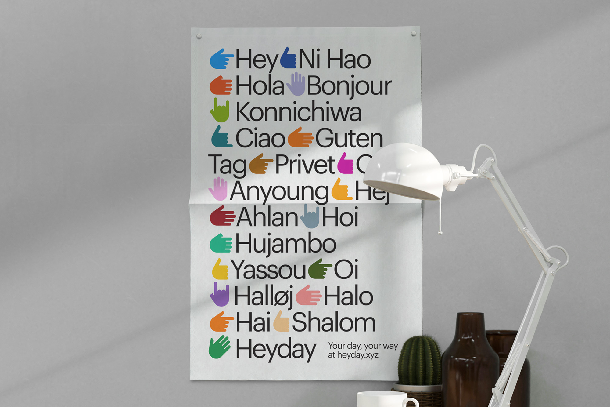 Colorful poster with greeting words in different languages alongside hand emojis, with a lamp and other objects in the background.
