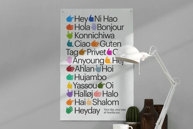 Colorful poster with greeting words in different languages alongside hand emojis, with a lamp and other objects in the background.