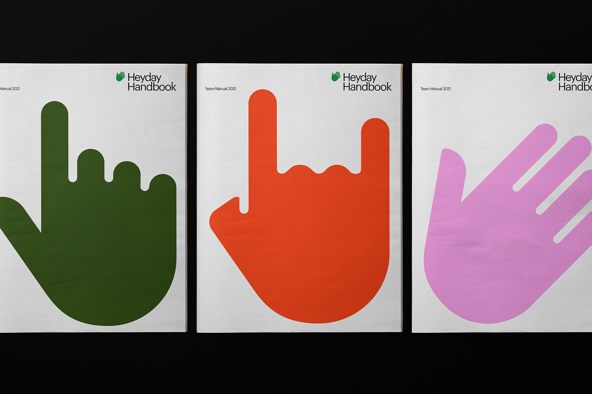 Three Heyday Handbook manuals in a row on a black surface, each featuring a different colored hand symbol on a white background.