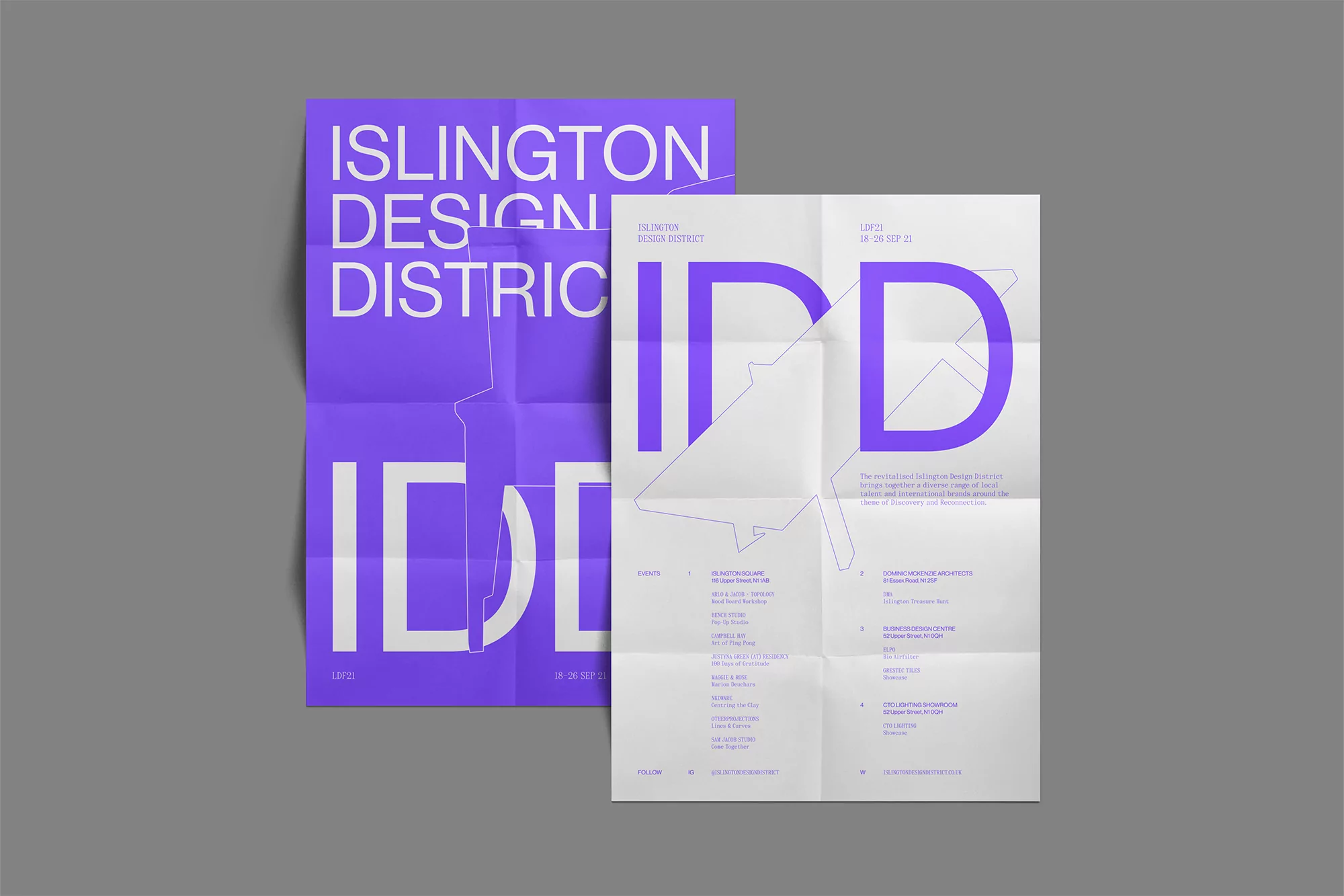 Two unfolded posters with purple and white text for the Islington Design District event; one is slightly crumpled, resting on gray surface.