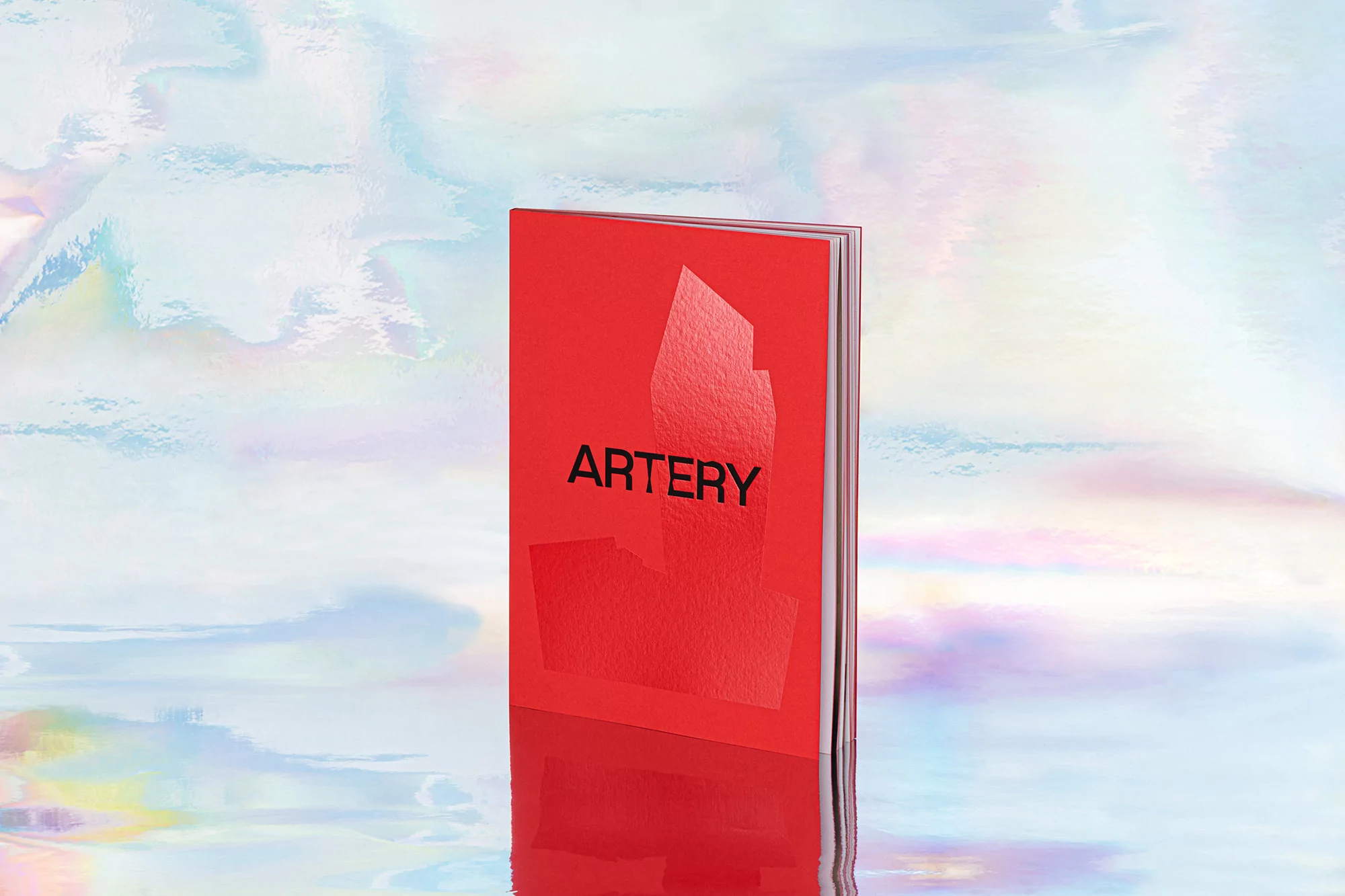 Close-up studio shot of a vibrant red hardcover book titled 'Artery' with a simple modern design against a soft holographic background.