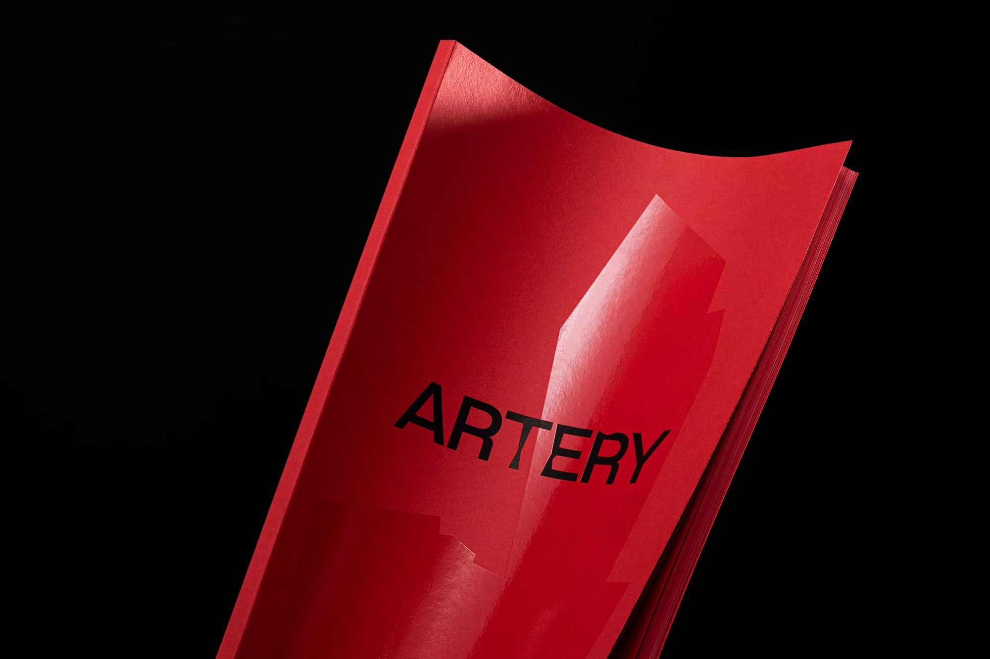 Elevated close-up of red magazine with the word 'ARTERY' on a black background showcases simple design and vibrant color.