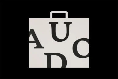 Graphic identity logo featuring bold black serif letters spelling AUDO on a light square background against black