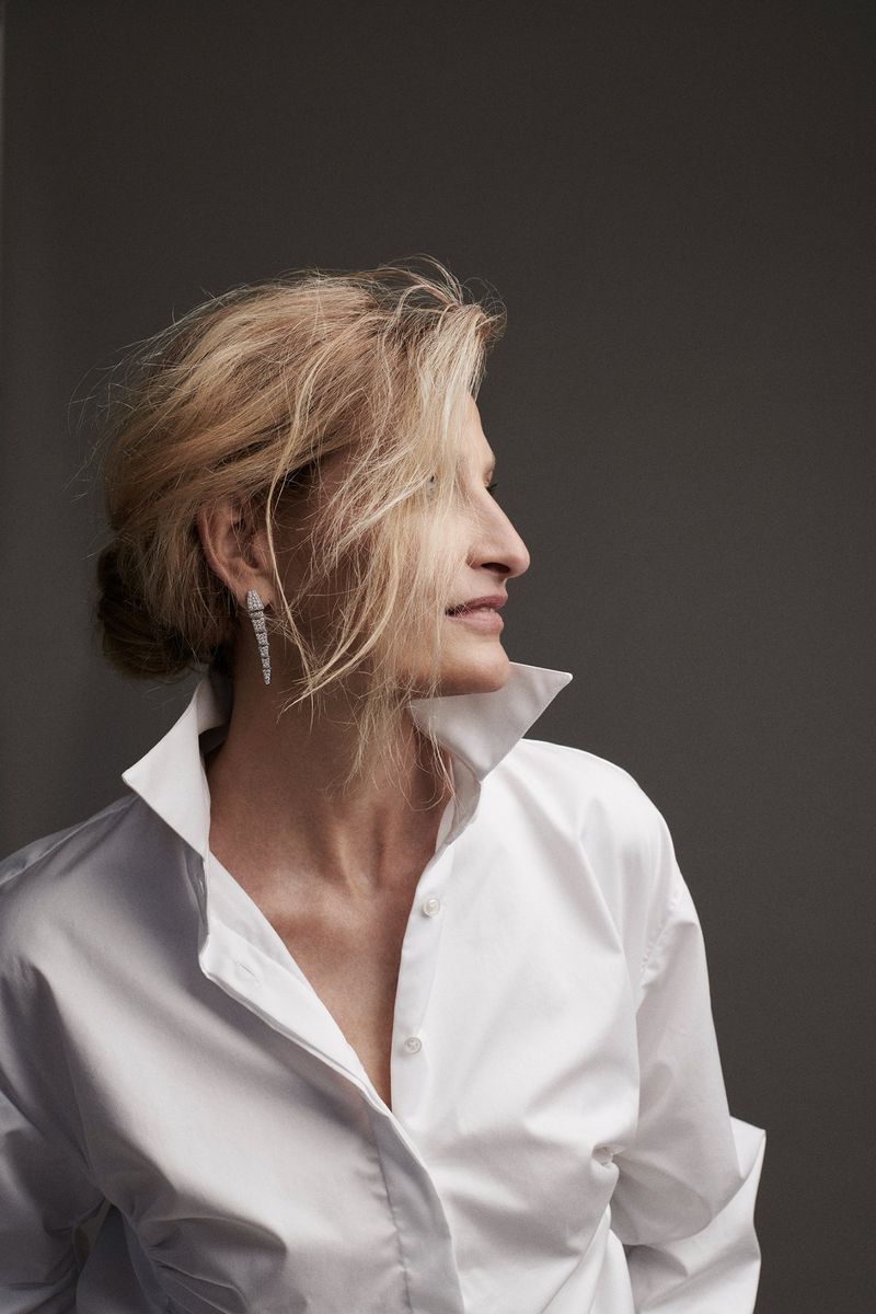 Portrait of a blonde adult female in a white collared shirt against a grey backdrop, showcasing fashion and beauty elements.
