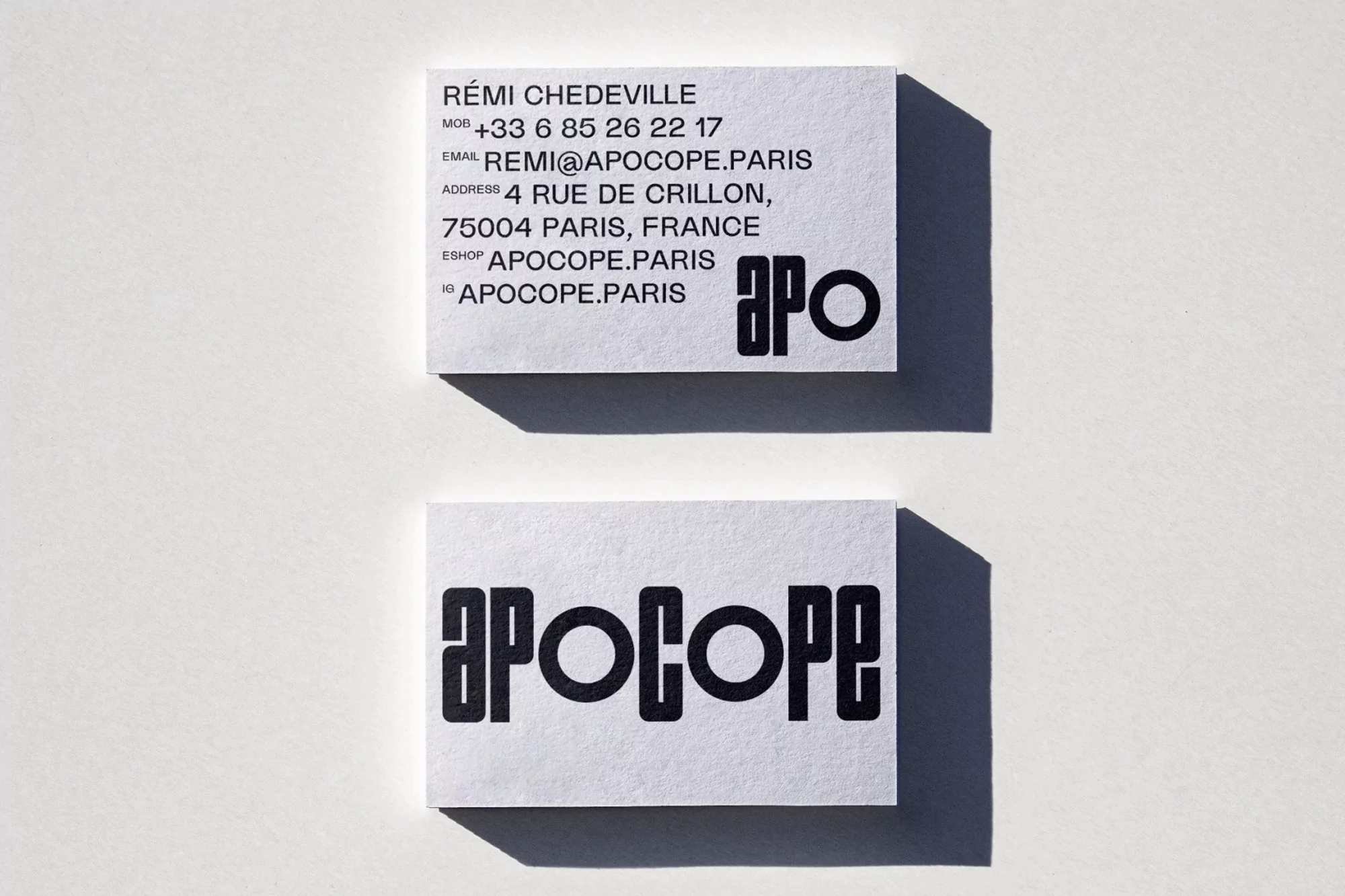 Two business cards with black minimalist typography on a white background under natural light showcasing Rémi Chedeville's contact details.