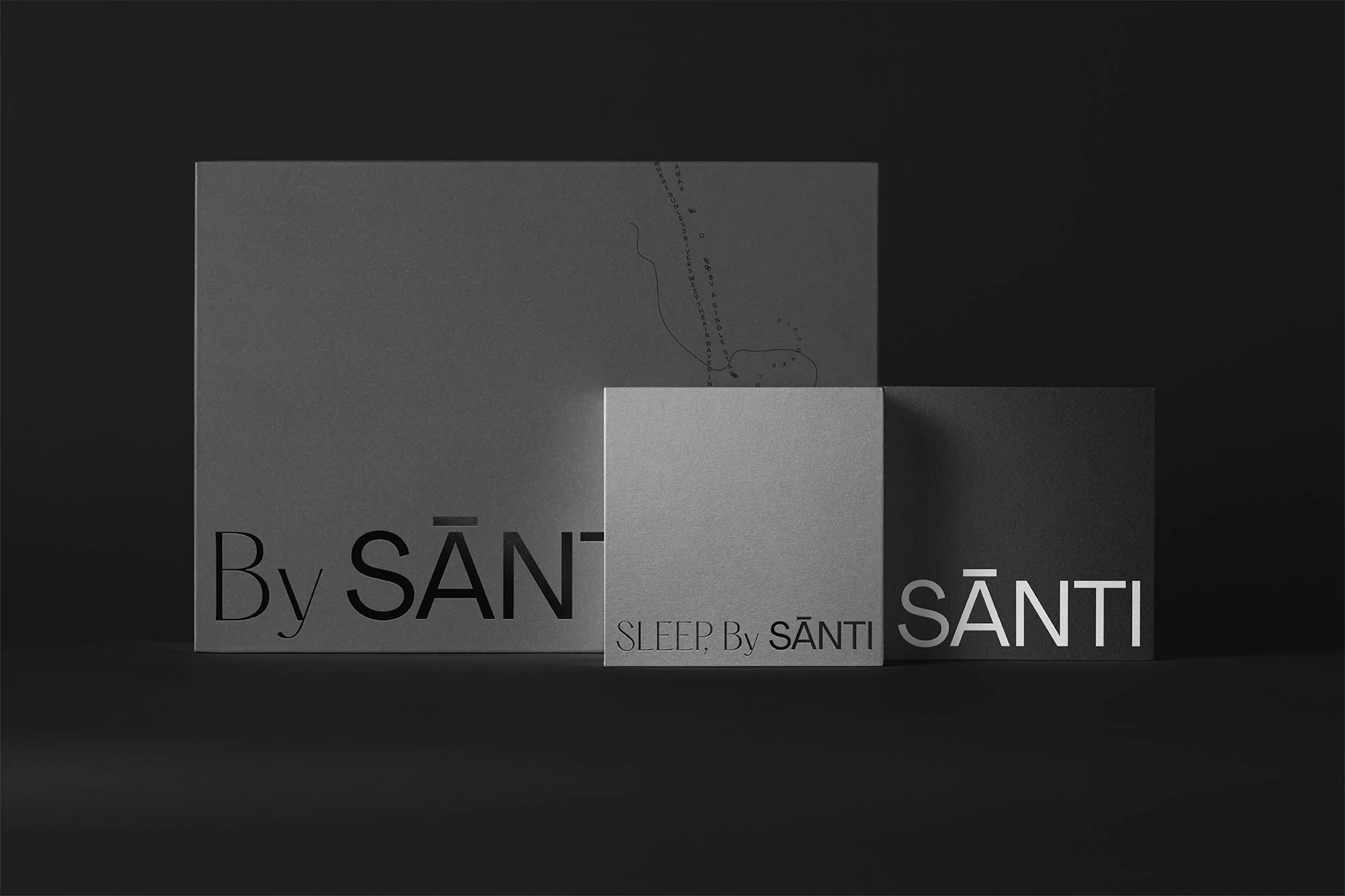 Three gray By Santi branded product boxes of different sizes arranged on a gray surface against a dark gray background.