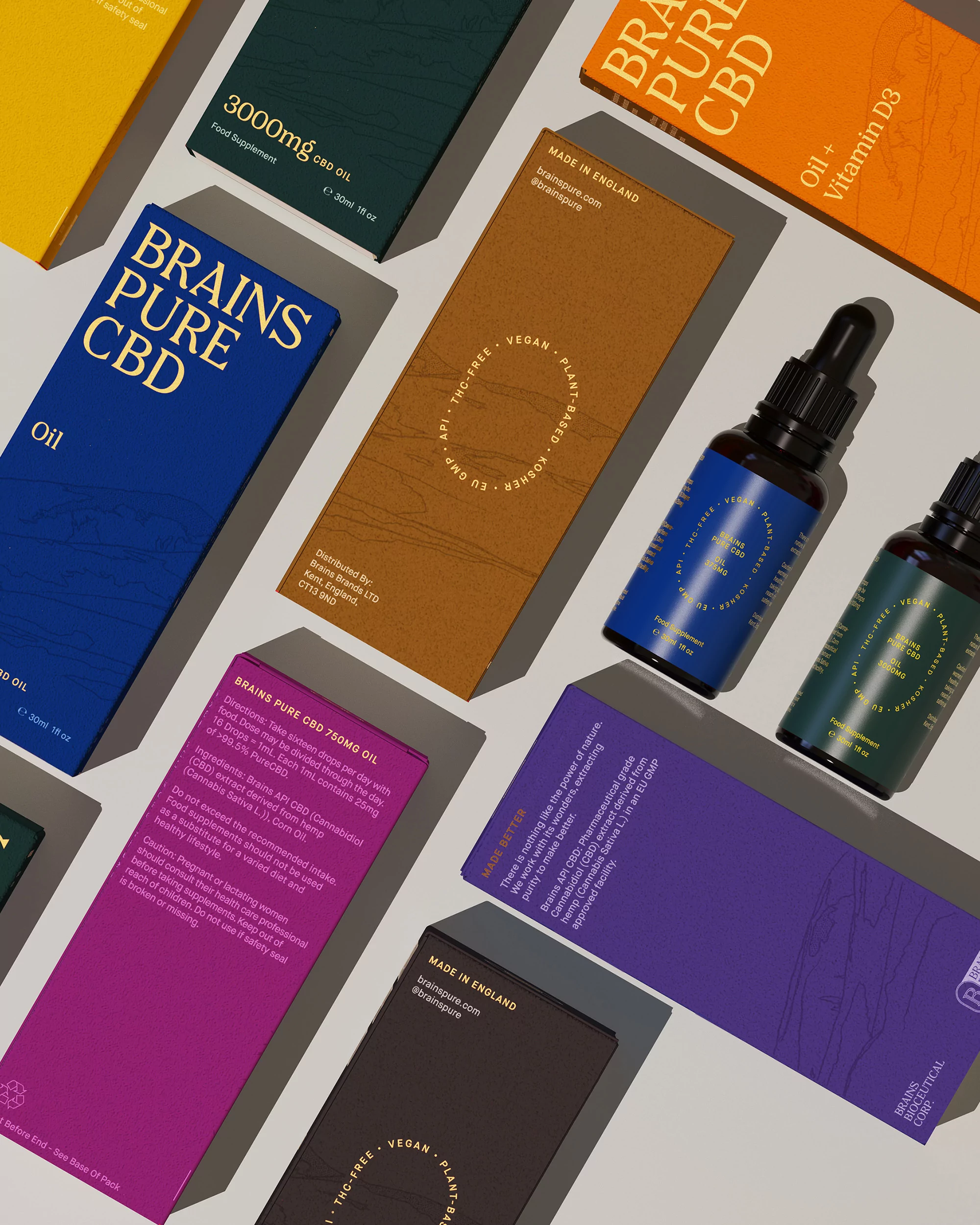 Overhead shot of CBD oil bottles and packaging in various colors arranged on a neutral surface in studio lighting for product photography.