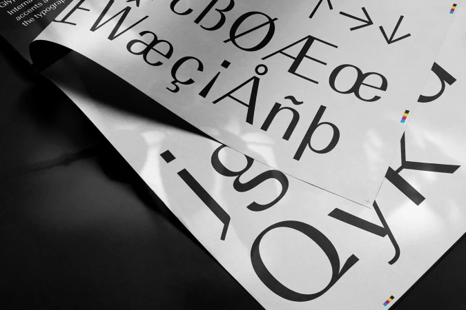 Close-up of printed typography sheets showing letterforms and special characters layered on a dark surface