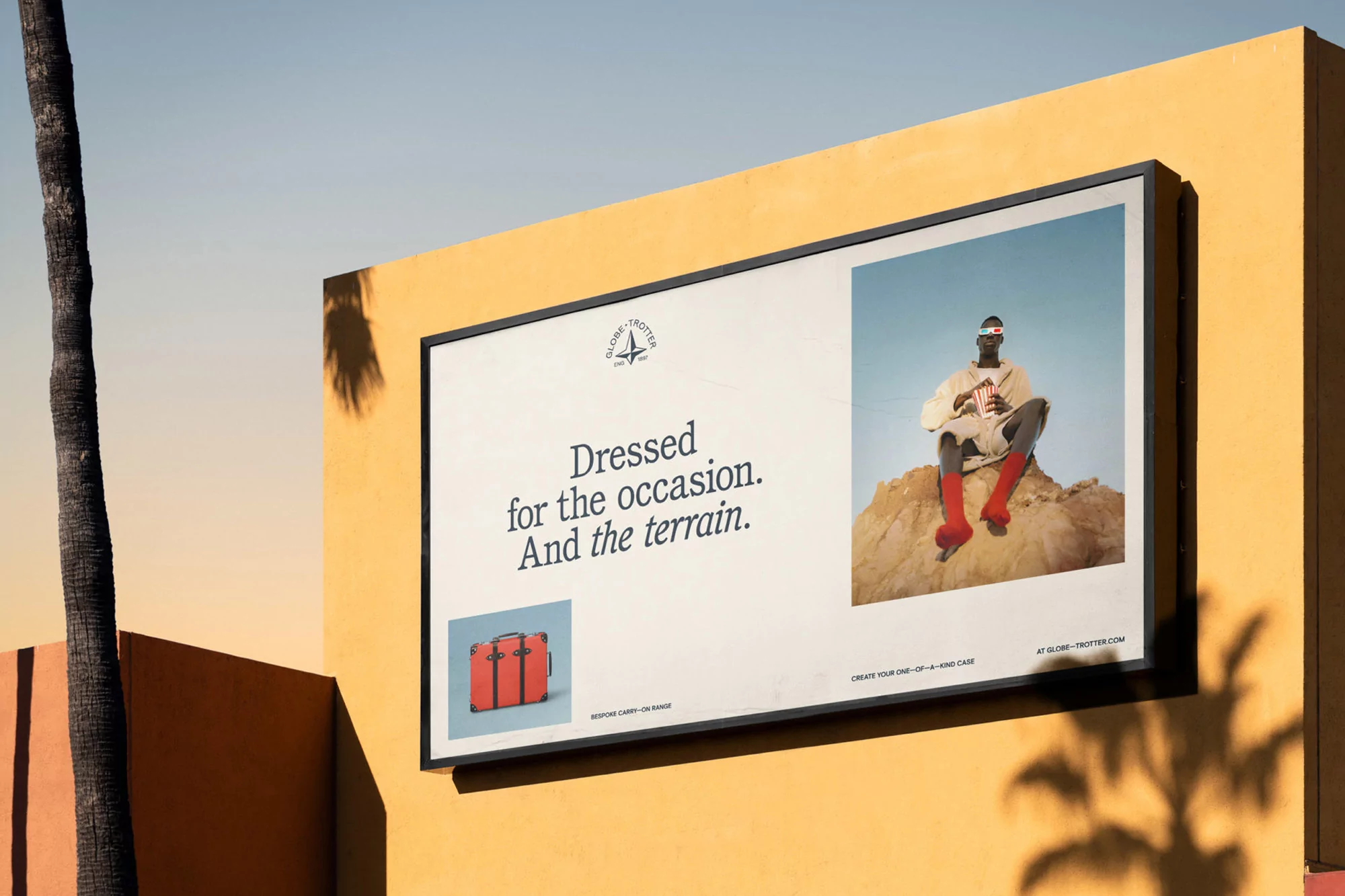 Billboard ad featuring a model in red boots, 3D glasses, popcorn, and a Globetrotter suitcase, against a yellow wall.