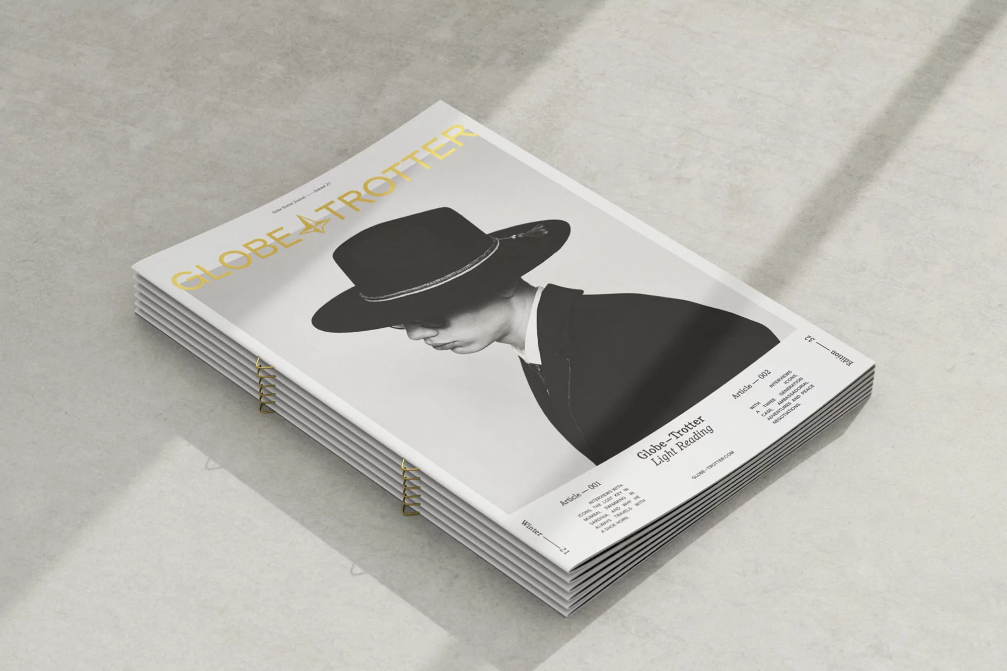Stack of Globe-Trotter magazines featuring a cover image of a person wearing a hat and suit, casting shadows on a light grey surface.