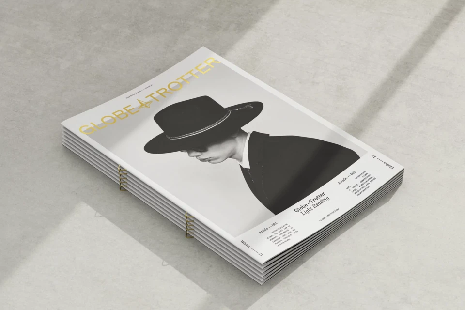Stack of Globe-Trotter magazines featuring a cover image of a person wearing a hat and suit, casting shadows on a light grey surface.