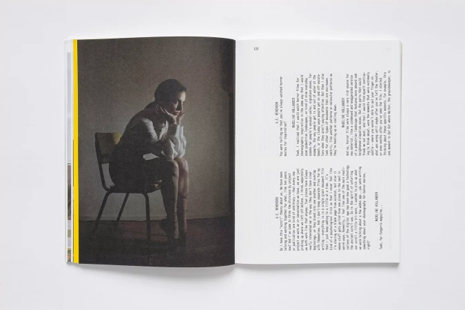 Seated woman, captured on a book page, rests her head on her hand in a contemplative pose; book open on a white surface.