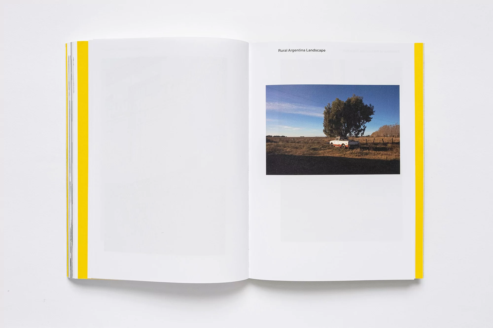 Open book displays a photograph of a rural Argentine landscape featuring a lone tree and a vehicle under a blue sky.
