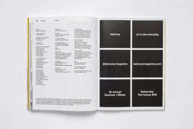 Open magazine spread showing editorial masthead text on the left and black design panels on the right against a plain surface.