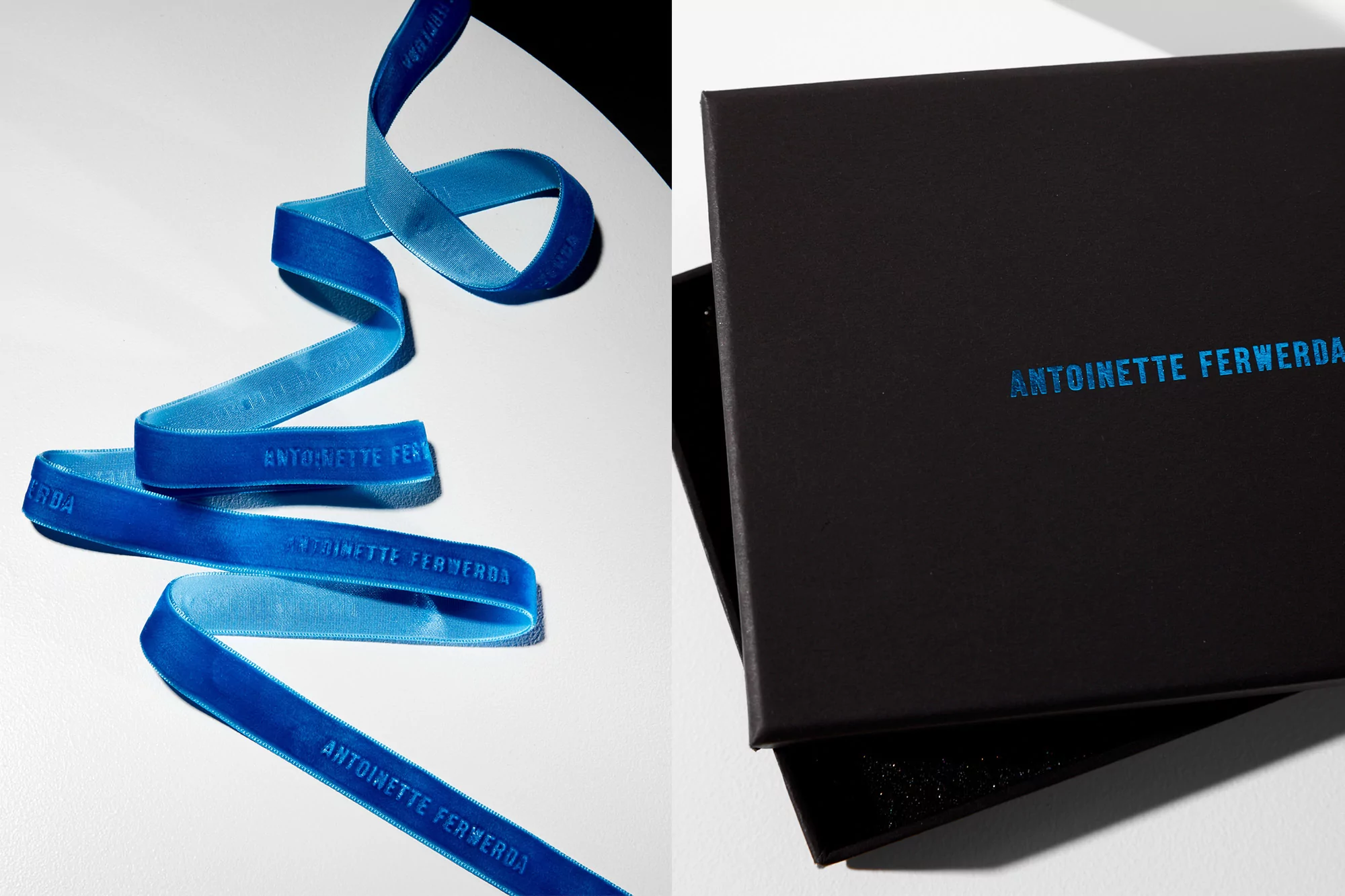 A blue ribbon with branding and a black box are set against a white backdrop in a product shot showcasing design and packaging.