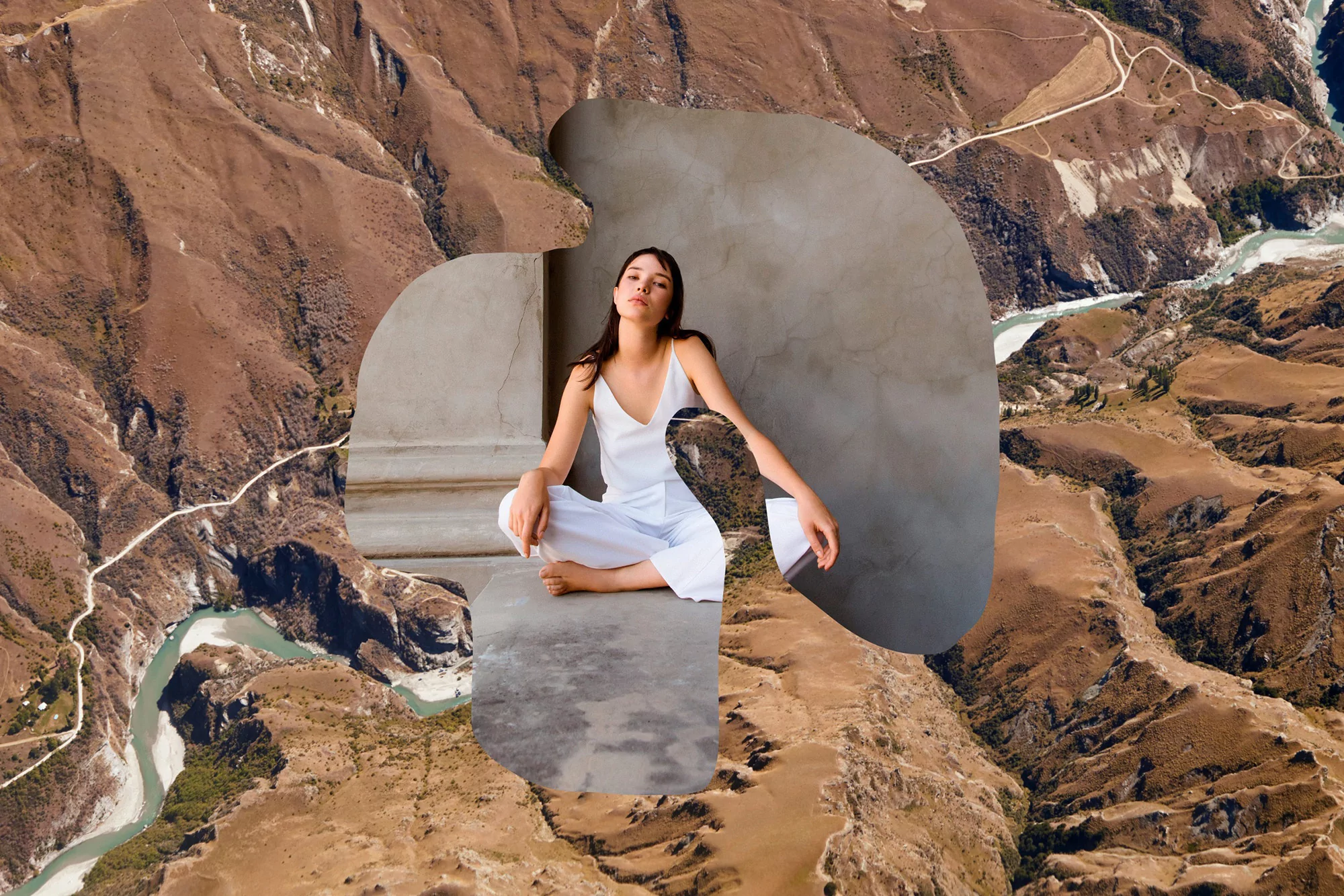 Woman in white outfit sitting cross-legged in front of concrete architectural element, with a mountain and river landscape collage background.