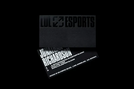 Black business card with debossed LoL Esports logo resting above another card with white typography for Jonathan Richardson