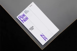 White booklet with purple typography and black Extra City logo resting on a dark grey textured surface.