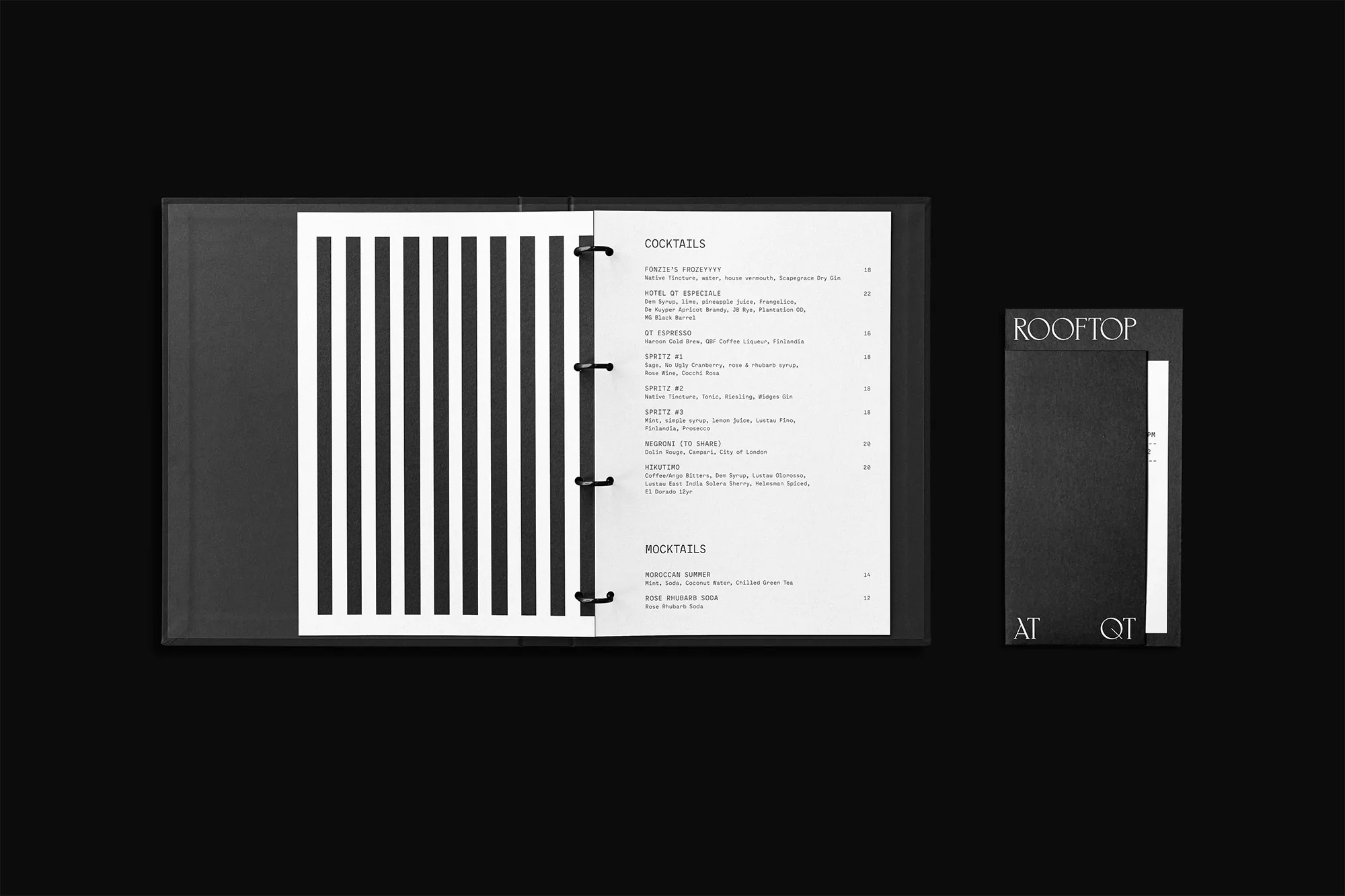 Open black menu on dark surface with bar and restaurant cocktail and mocktail list, alongside smaller menu with "Rooftop at QT" text.