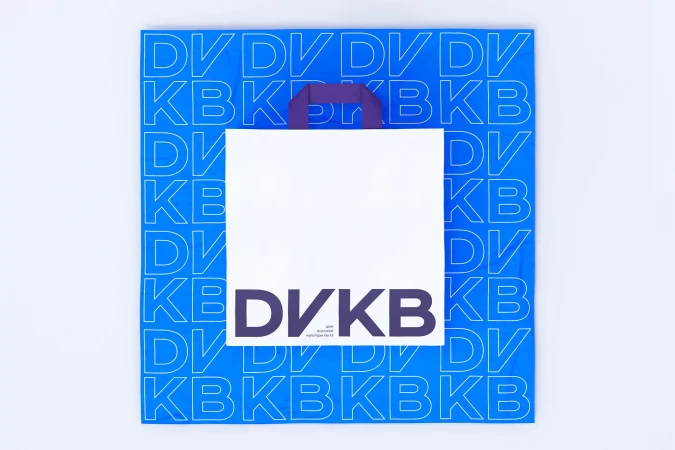 Square shot of a white shopping bag with blue patterned background and purple handles. Isolated image on a white background.