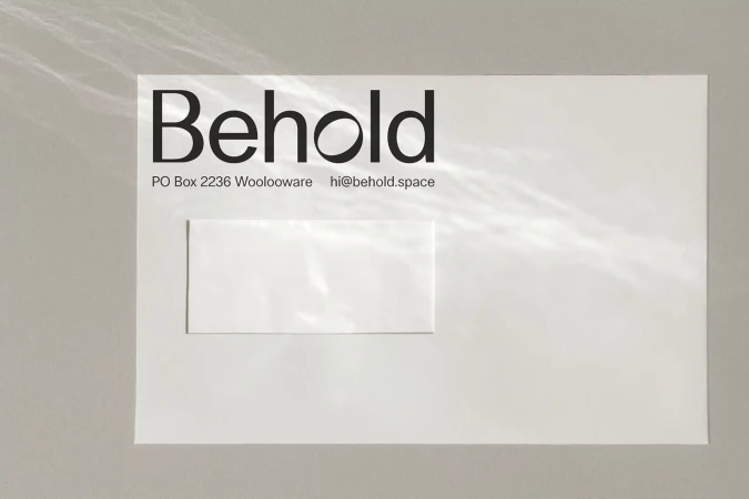White envelope on grey surface with black company logo and address details, abstract light patterns on envelope surface.