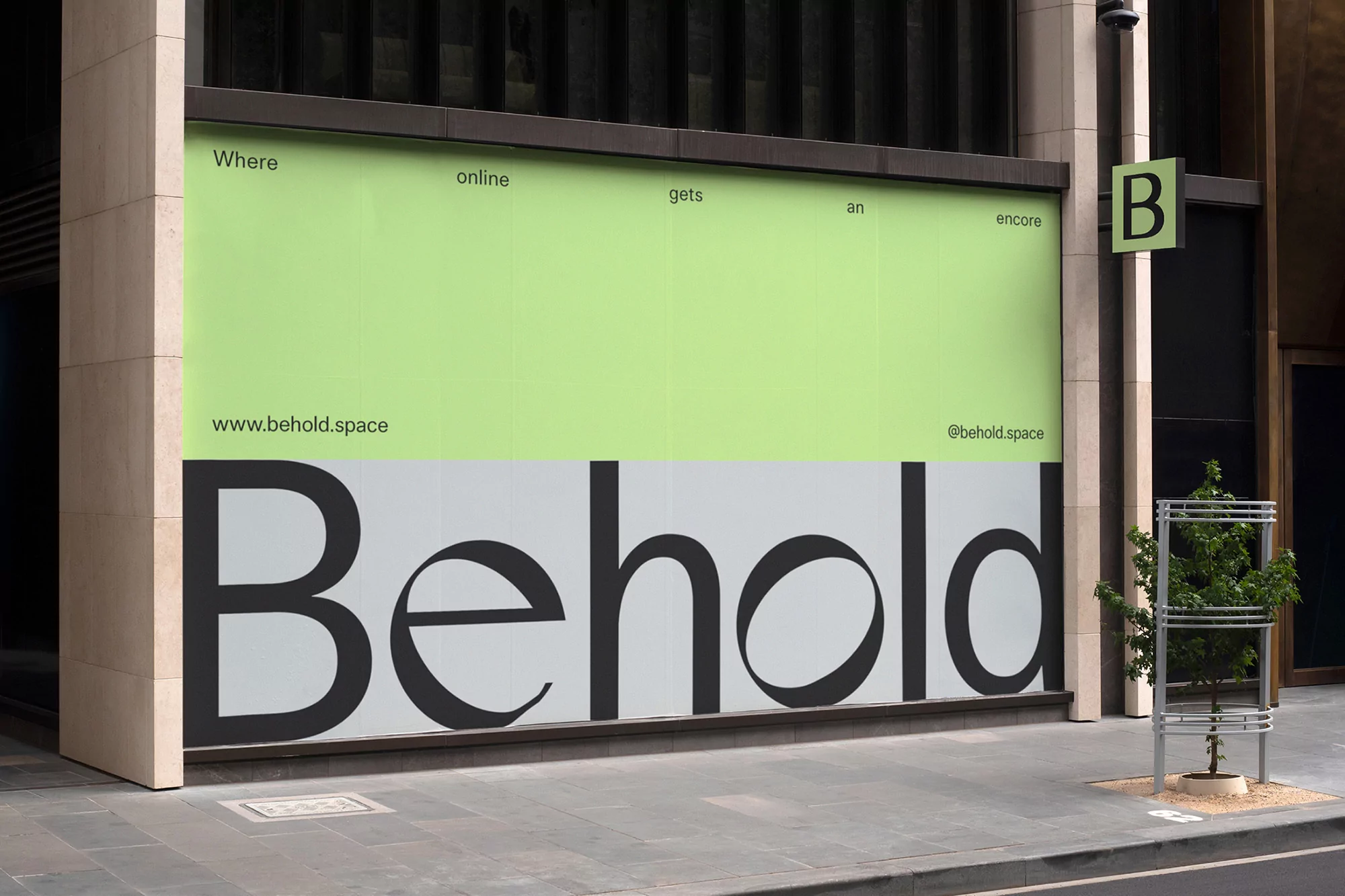 Building facade featuring large 'Behold' lettering and green upper section with promotional website and social media information displayed.