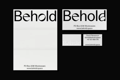 Behold brand identity stationery layout featuring custom typography on white paper against a black background.