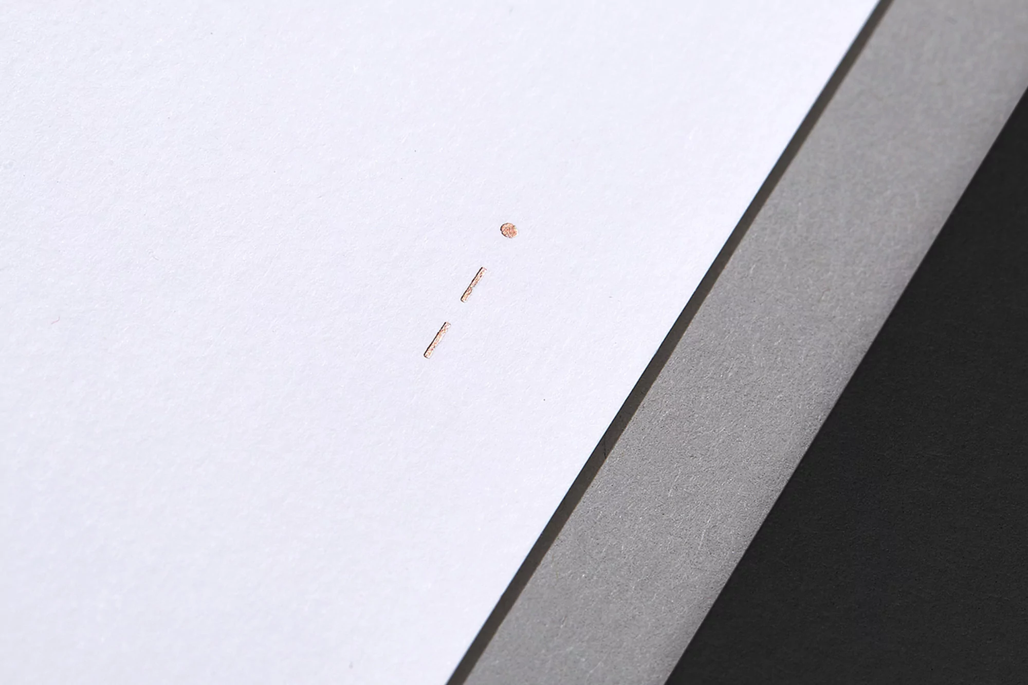 Close-up abstract of white and gray paper with staple marks and linear shadow, showing minimalist texture and contrasting tones.