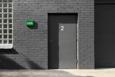 Grey painted brick wall with a dark door marked with the number two and a green GSS sign