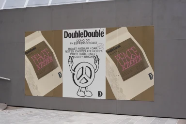 Large exterior wall poster featuring DoubleDouble coffee branding with Peace Keeper coffee bag illustrations