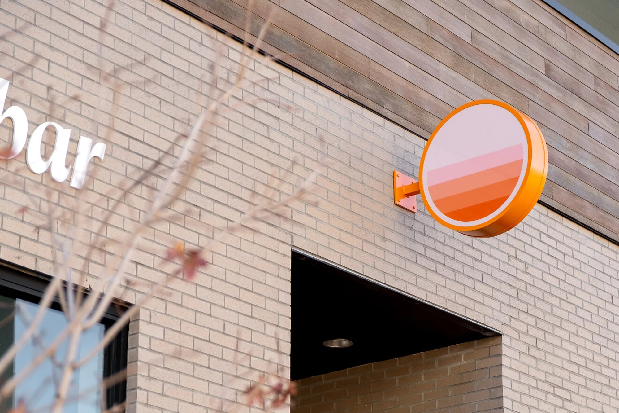 Exterior of building with an orange, circular sign and architectural details, showcasing a modern and inviting business facade.