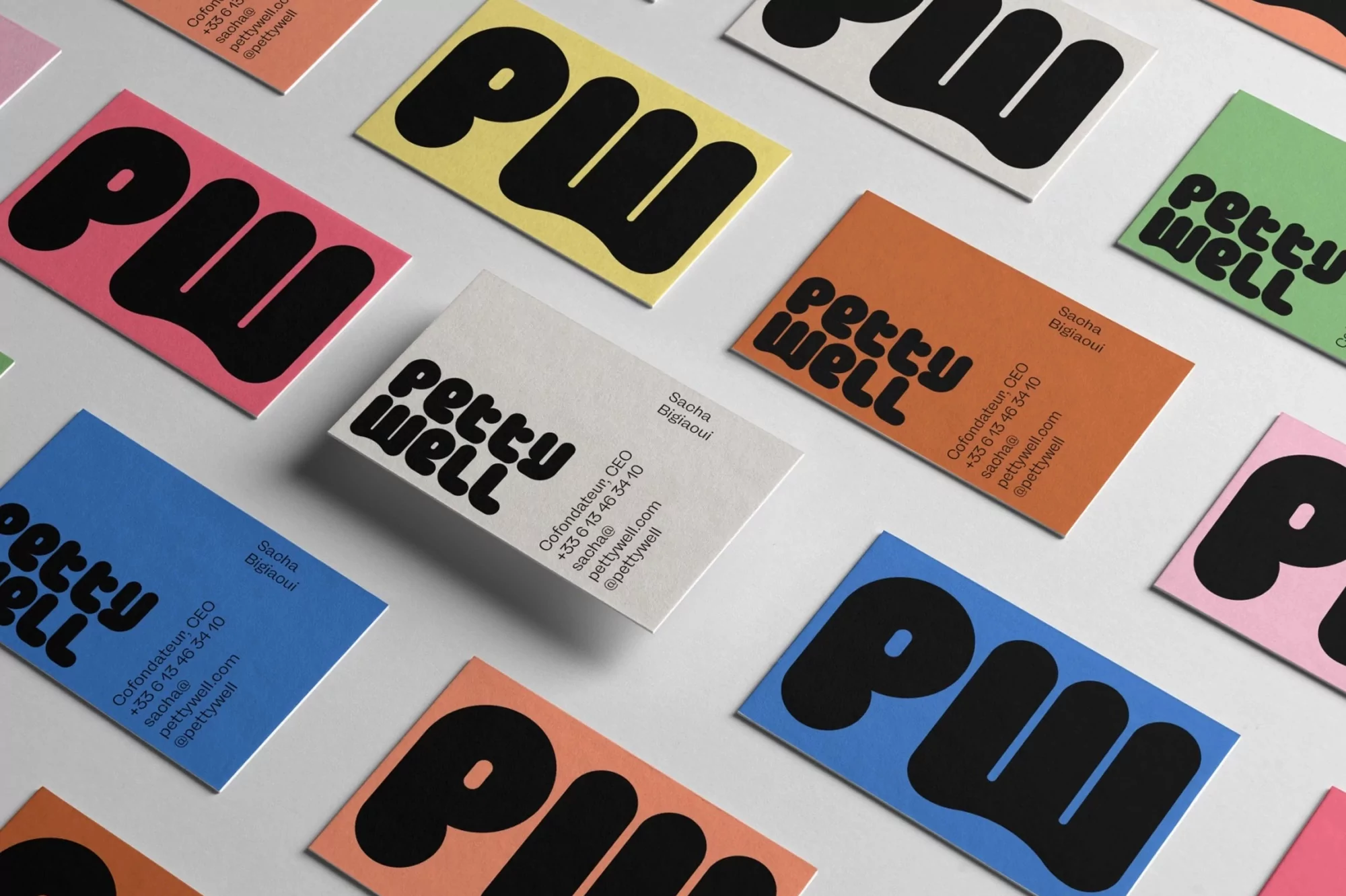 Scattered business cards with colorful backgrounds and bold text, showcasing branding with modern typography and a clean, minimalist design.