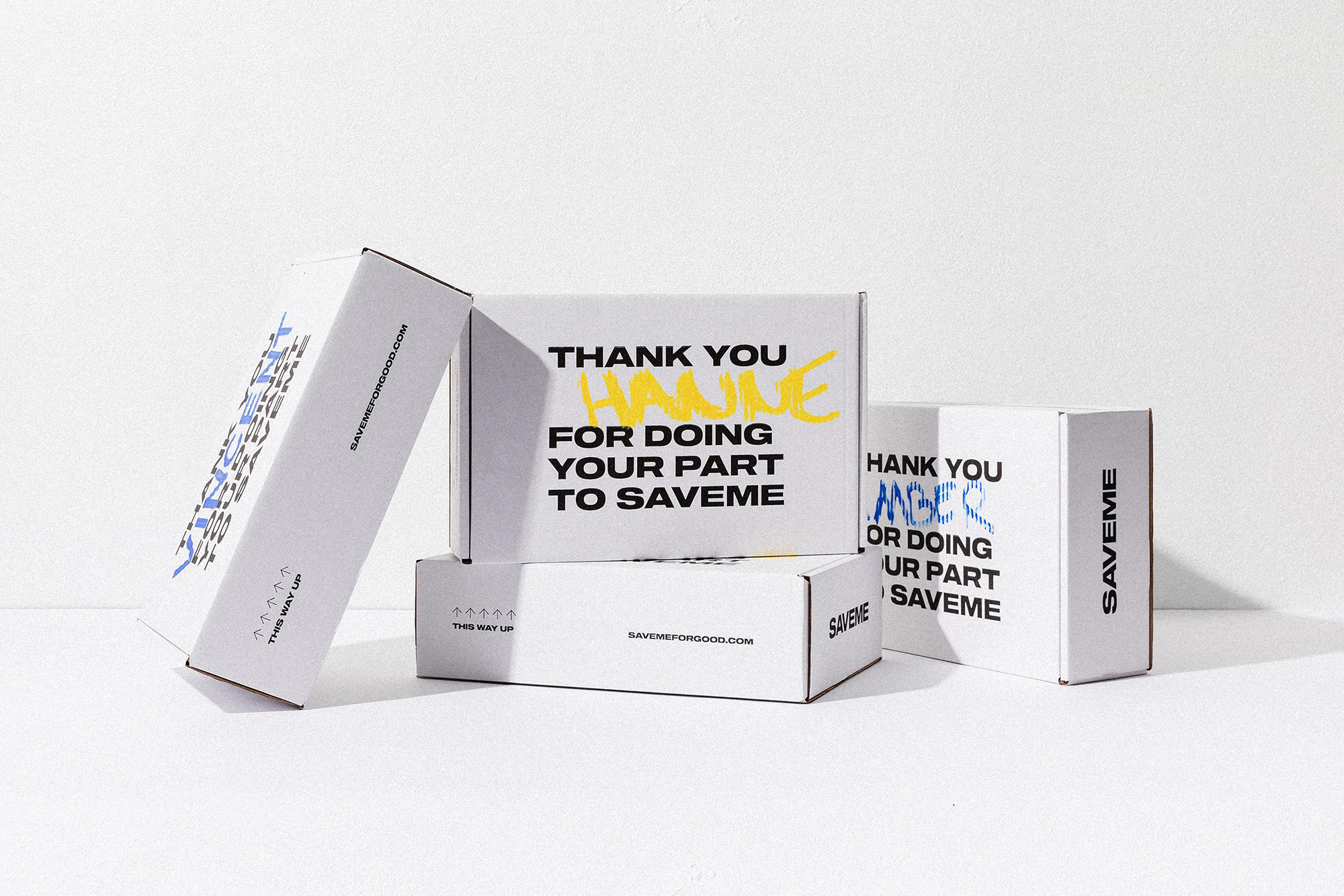 Stack of white cardboard boxes with colorful handwritten text, arranged in a studio setting against a white background. 