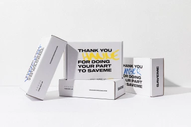 White branded packaging boxes with typography arranged in a stack against a plain textured background.