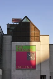 Exterior facade of MAC Montreal featuring a large vibrant exhibition banner with text against a concrete wall under clear blue sky.