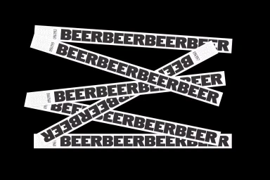 Multiple white paper wristbands with repeating black text arranged diagonally on a solid black background.