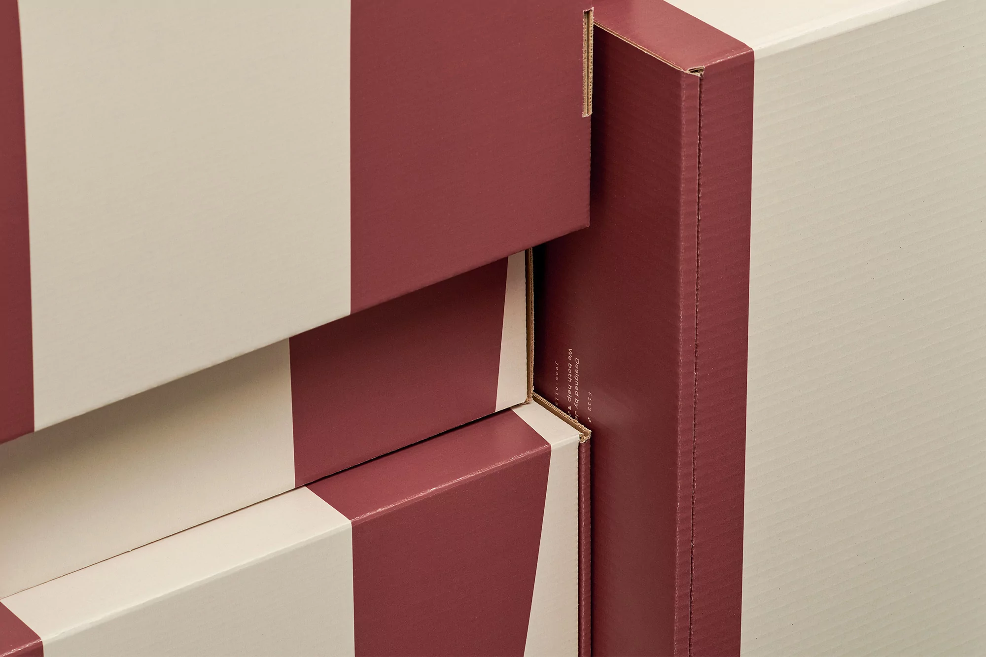 Stack of maroon and white striped cardboard boxes in a close-up shot, highlighting the packaging and pattern.