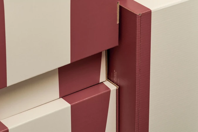 Close-up of stacked burgundy and white striped cardboard boxes designed by Jens Nilsson for Packhelp.