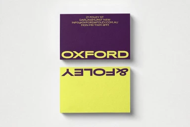 Two business cards with purple and yellow typography displayed against a light textured background