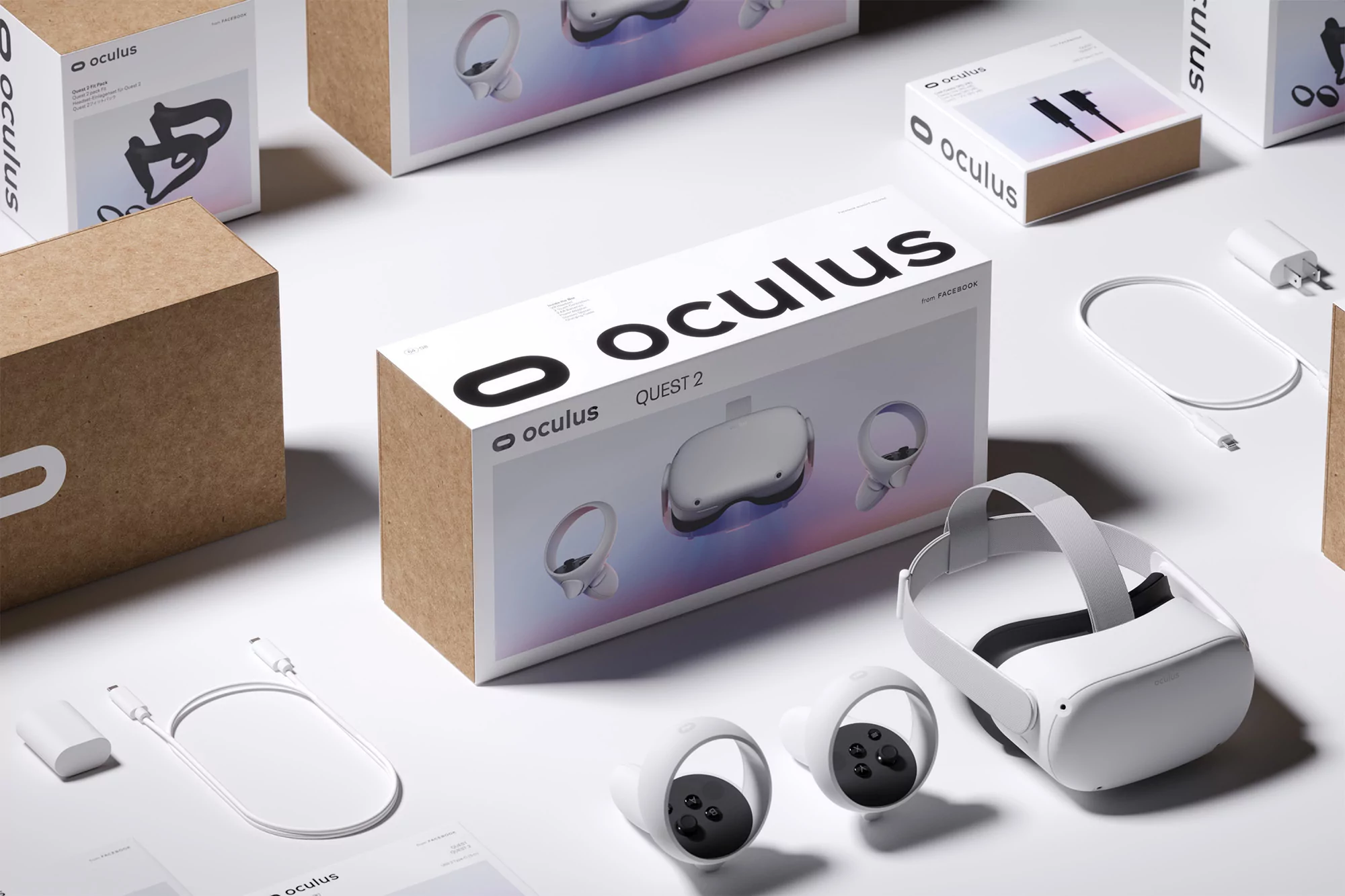 Oculus Quest 2 VR headset displayed with its box, controllers, charging cable, and power adapter on a bright white background.