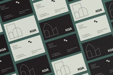 Flat lay of black and white business cards with minimalist architectural line drawings arranged on a green surface.