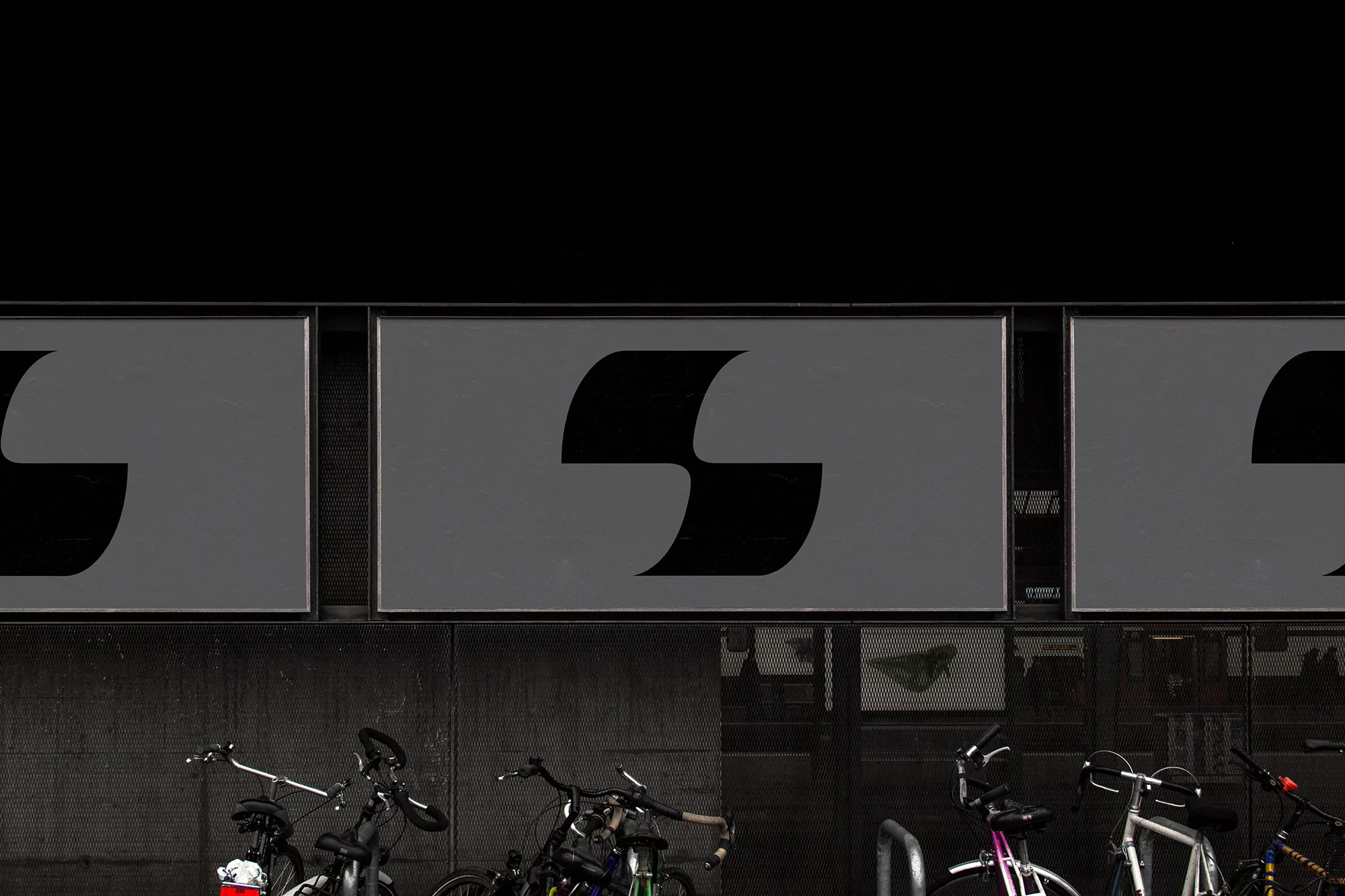 Modern geometric logo design displayed on three gray billboards above parked bicycles against a dark urban background.