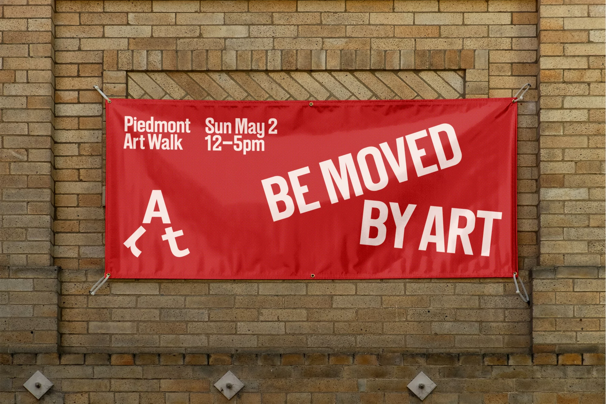 Red banner on a brick wall advertises Piedmont Art Walk on May 2 from 12 to 5 pm with the text 'Be Moved by Art'.
