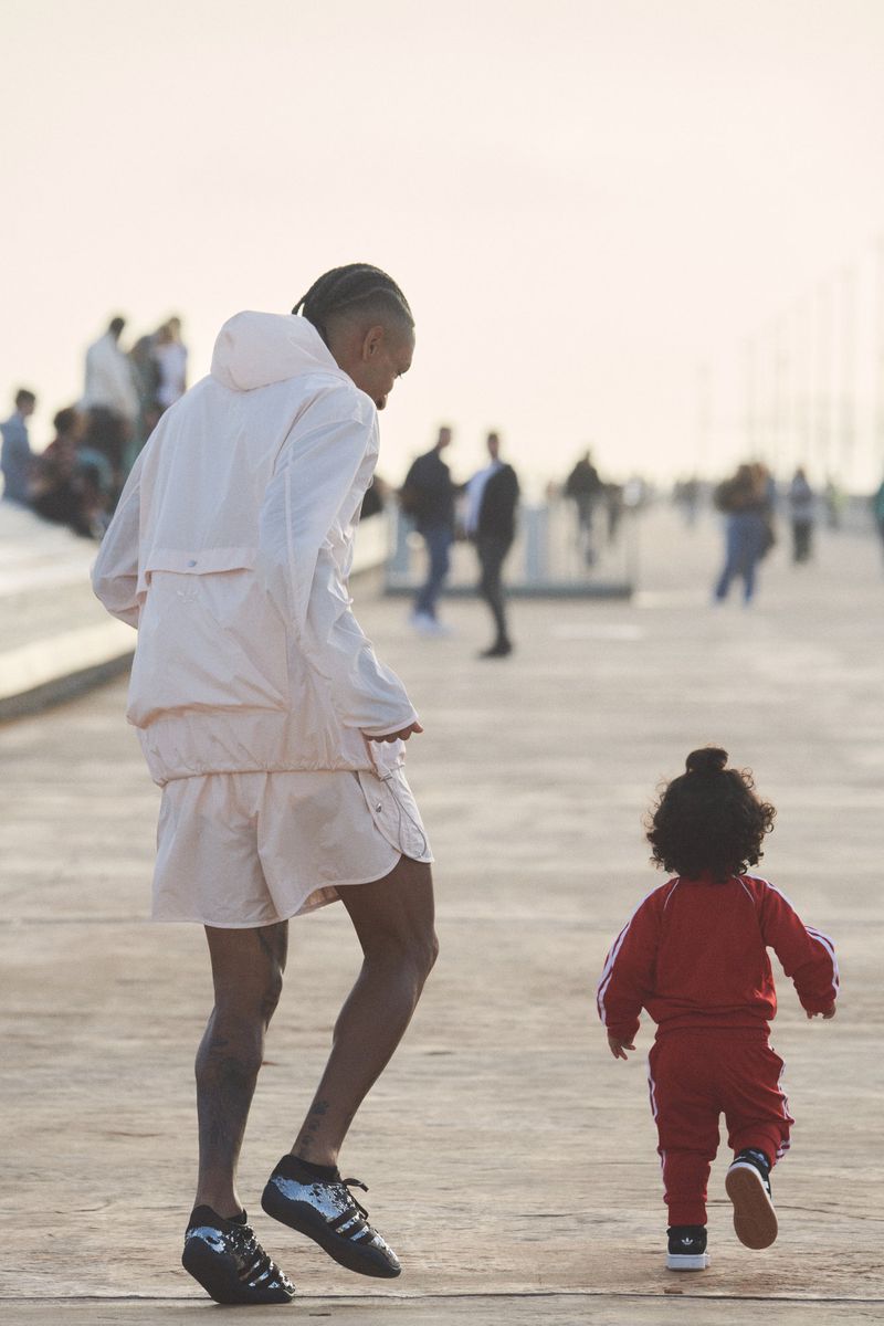 Adult and child in athletic attire walking on a grey walkway. Several out-of-focus people in background. Light airy setting.
