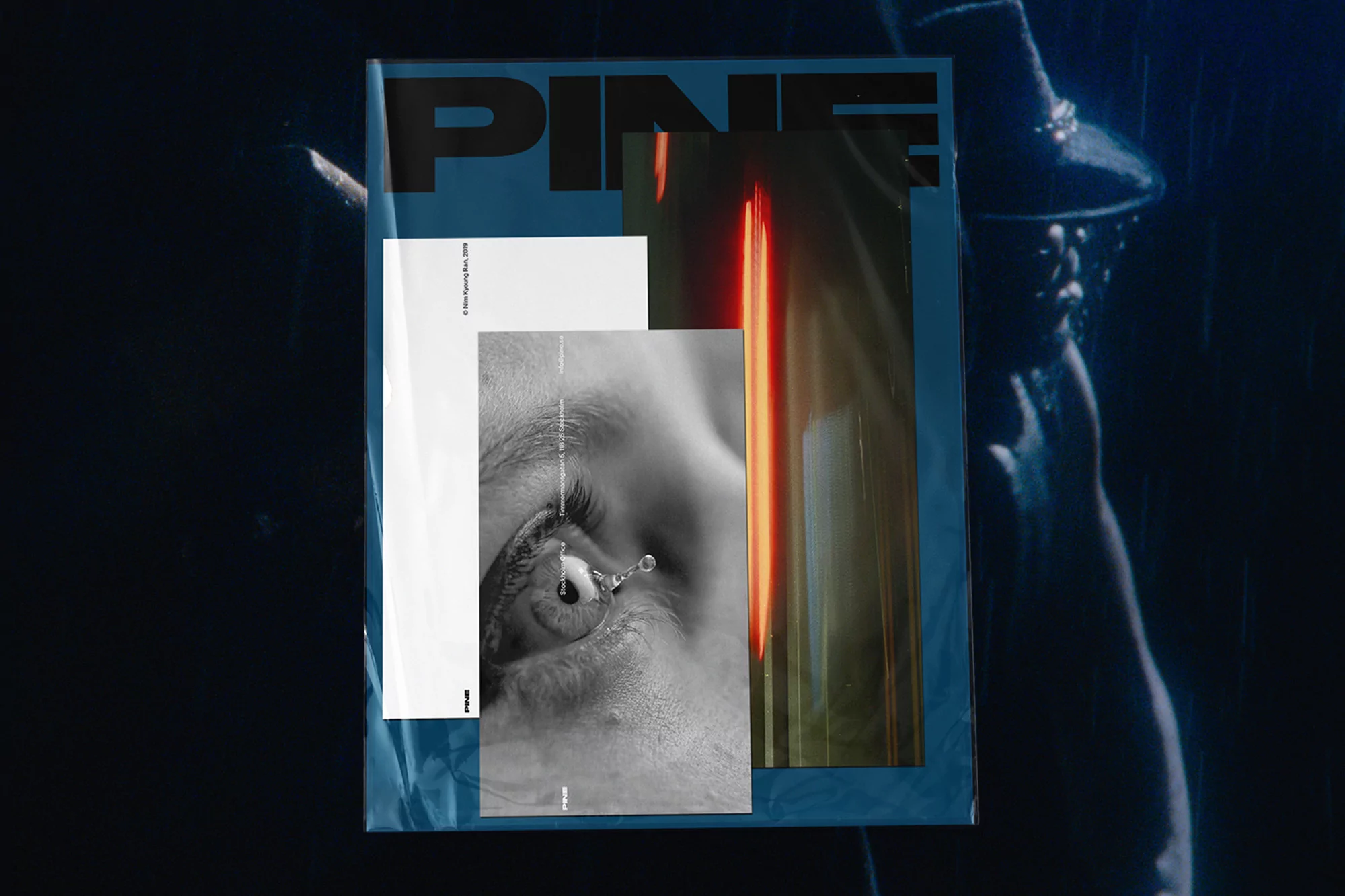 Magazine cover featuring a close-up of a eye with a tear drop, overlaid with blurred lights and a figure with a dark hat.