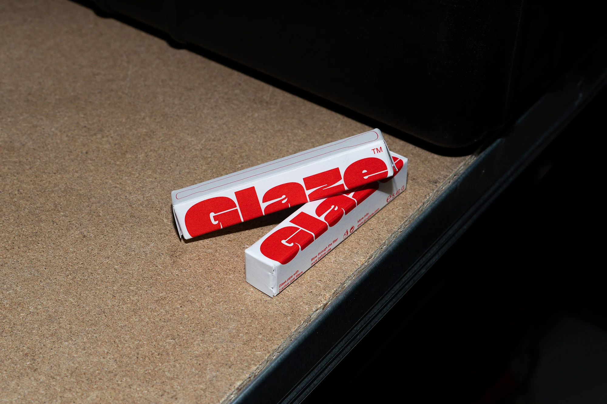 Close-up of two Glaze packages stacked on a surface, featuring red text on a white background in indoor lighting.