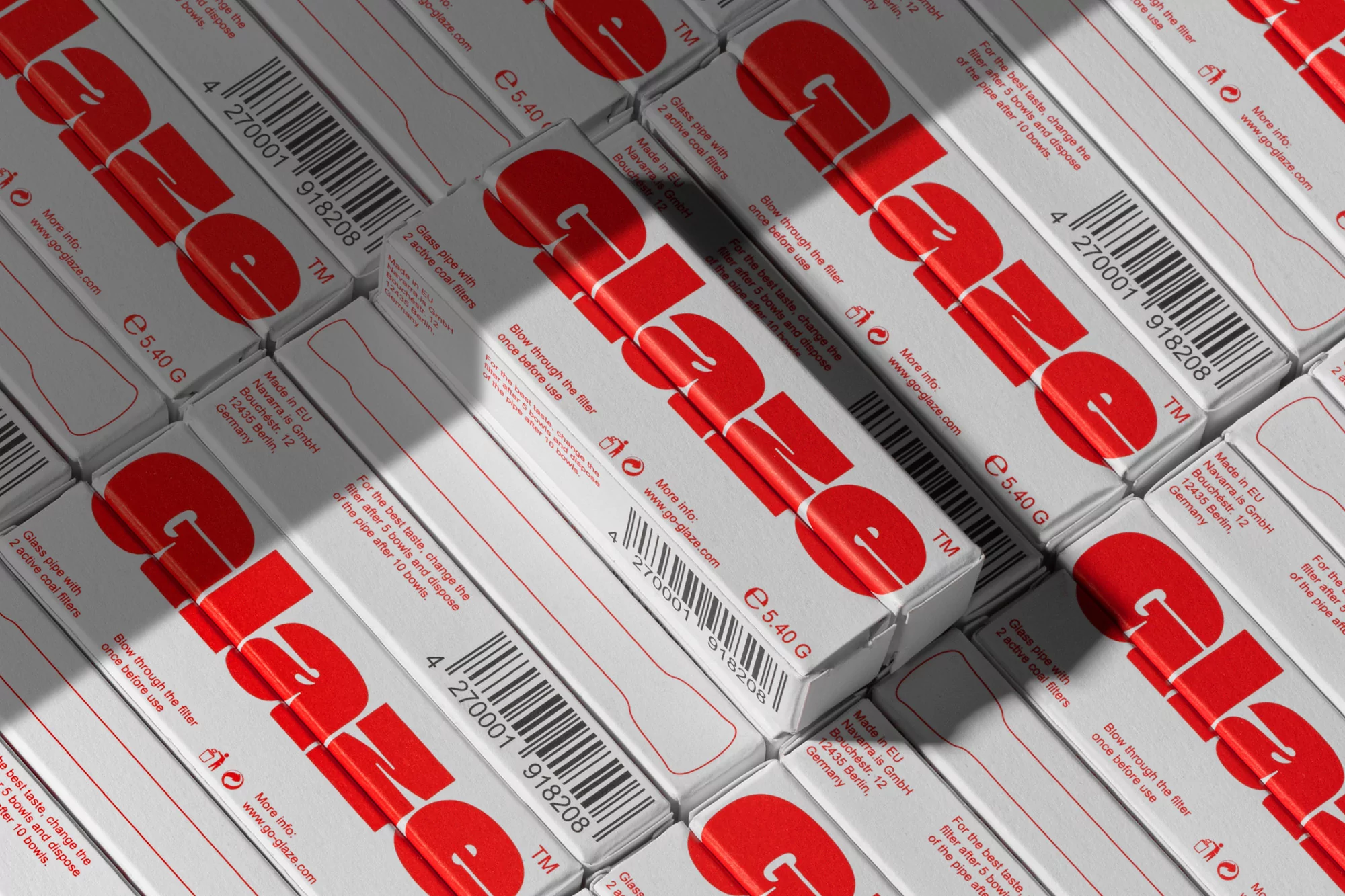 Multiple white product boxes featuring 'Glaze' in red font, a barcode, and product information, stacked on a surface in a studio setting.