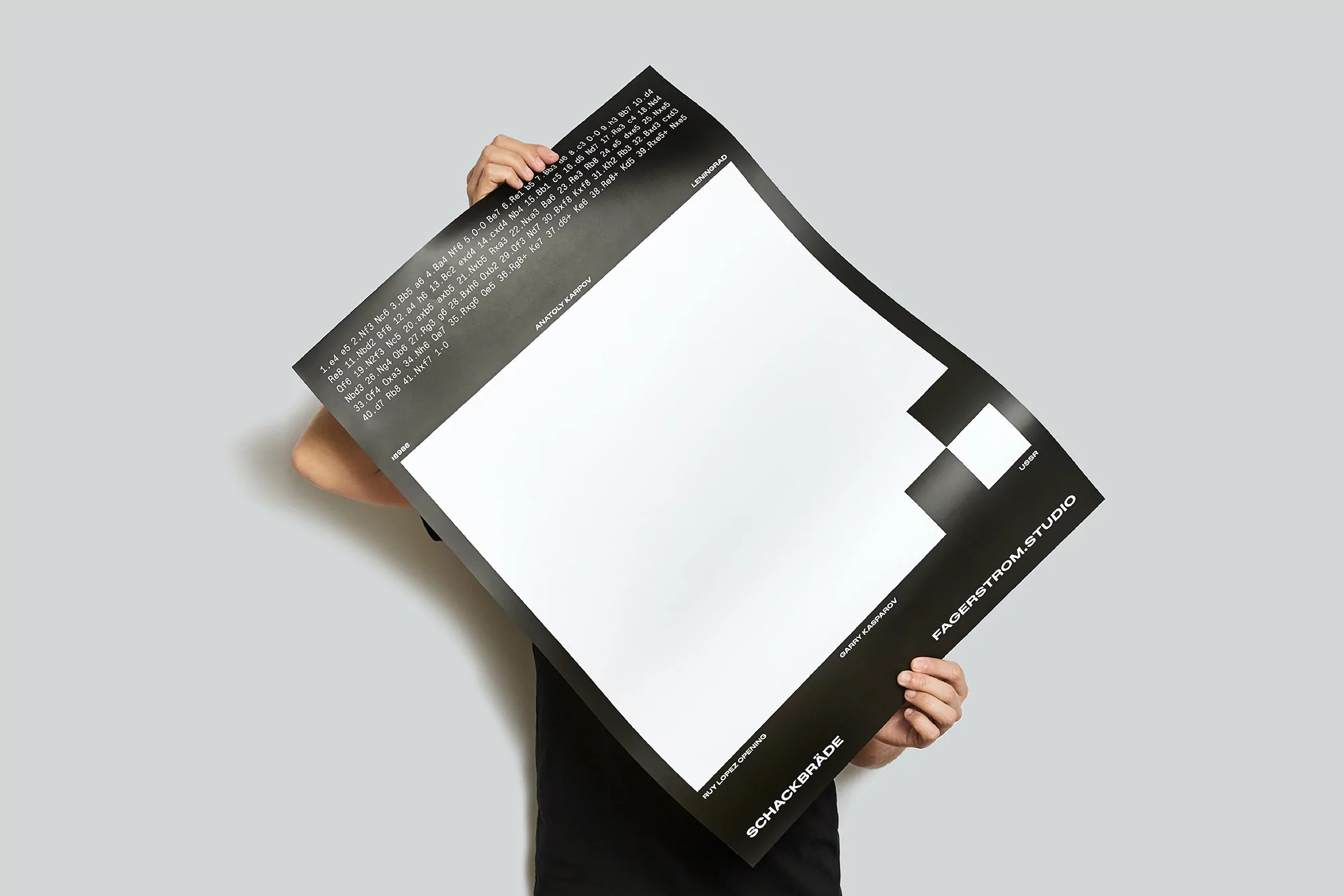 Person holding a black and white poster with text, displaying a modern and minimalist design against a neutral gray background.